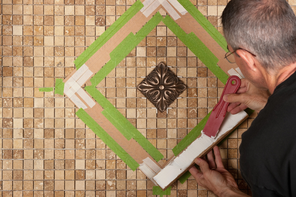 Pose d’un motif décoratif au centre d’une mosaïque de travertin au sol